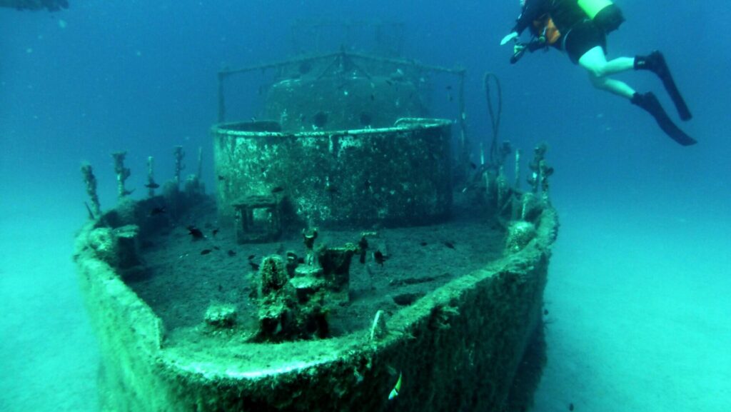 Schiffswrack unter Wasser mit Tauchern drumherum