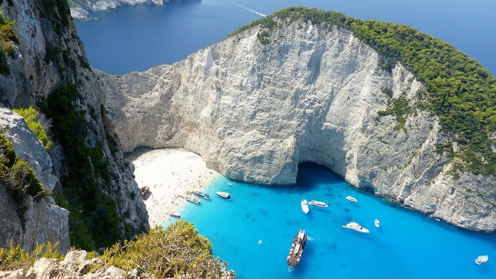 Blick von oben auf eine Bucht mit türkisblauem Wasser und einigen Booten, traumhafter Ausblick