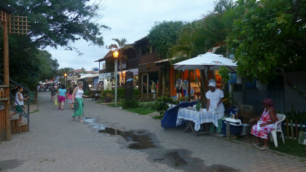 Weg mit kleinen Geschäften, am Anfang steht ein Stand, an dem zwei Frauen etwas verkaufen