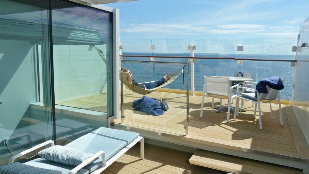 Balkon der Himmel & Meer Suite mit einem Tisch und Stühlen und einer Hängemate