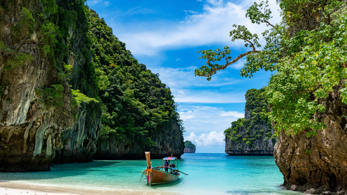 wunderschöner Strand in Thailand mit einem kleinen Boot und grünen Felsen drumherum