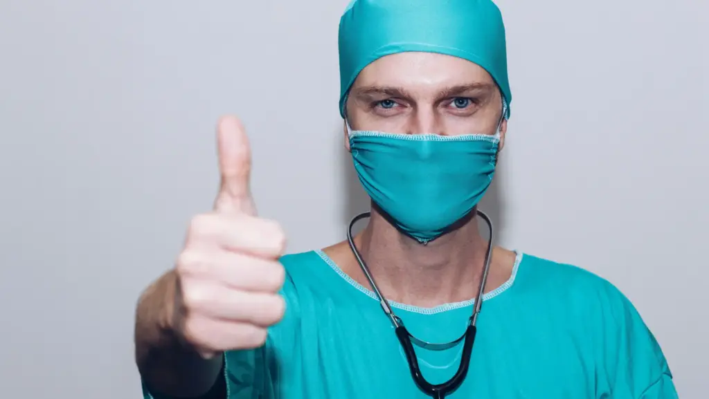 Arzt mit Kittel und Maske zeigt Daumen hoch