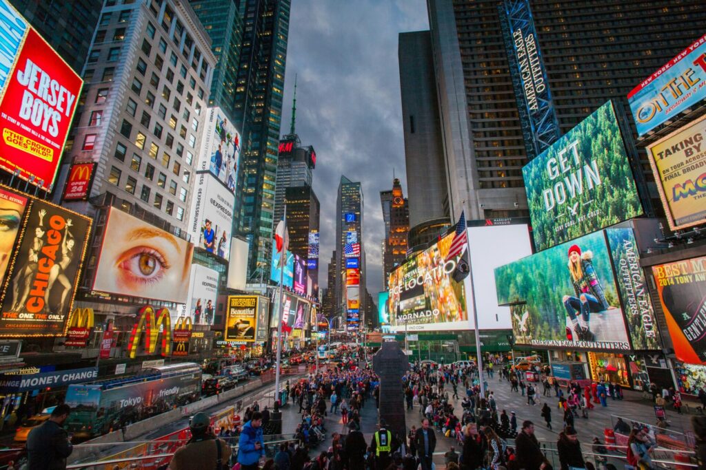 Times Square mit leuchtenden Schildern und großer Menschenmenge