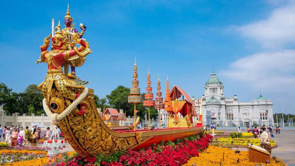 gold-verziertes Boot auf einem Blumenbeet, im Hintergrund ein weißer Tempel
