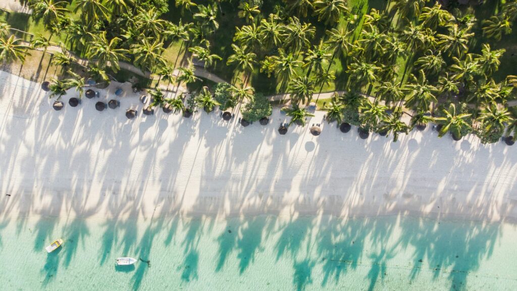 weißer Sandstrand mit klarem türkisfarbenen Wasser und vielen Palmen