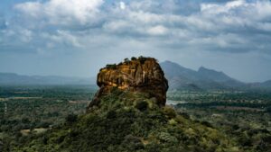 einzelner hoher Felsen in einer flachen grünen Landschaft