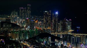Skyline bei Nacht mit vielen Hochhäusern, rechts ein Hafen